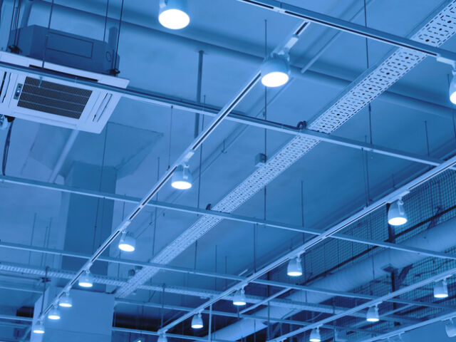 Ceiling with bright lights in a modern warehouse, shopping center building, office or other commercial real estate object. Directional LED lights on rails under the ceiling. Tinted.