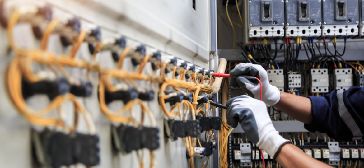 Commercial electrician wearing safety gloves holding a red and a black wire