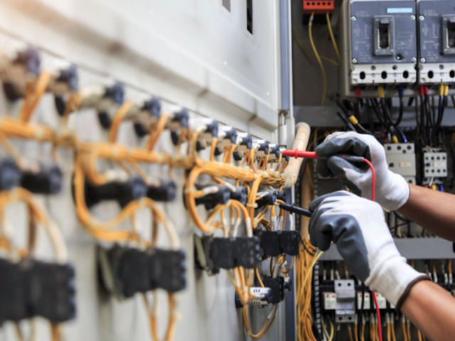 Commercial electrician wearing safety gloves holding a red and a black wire